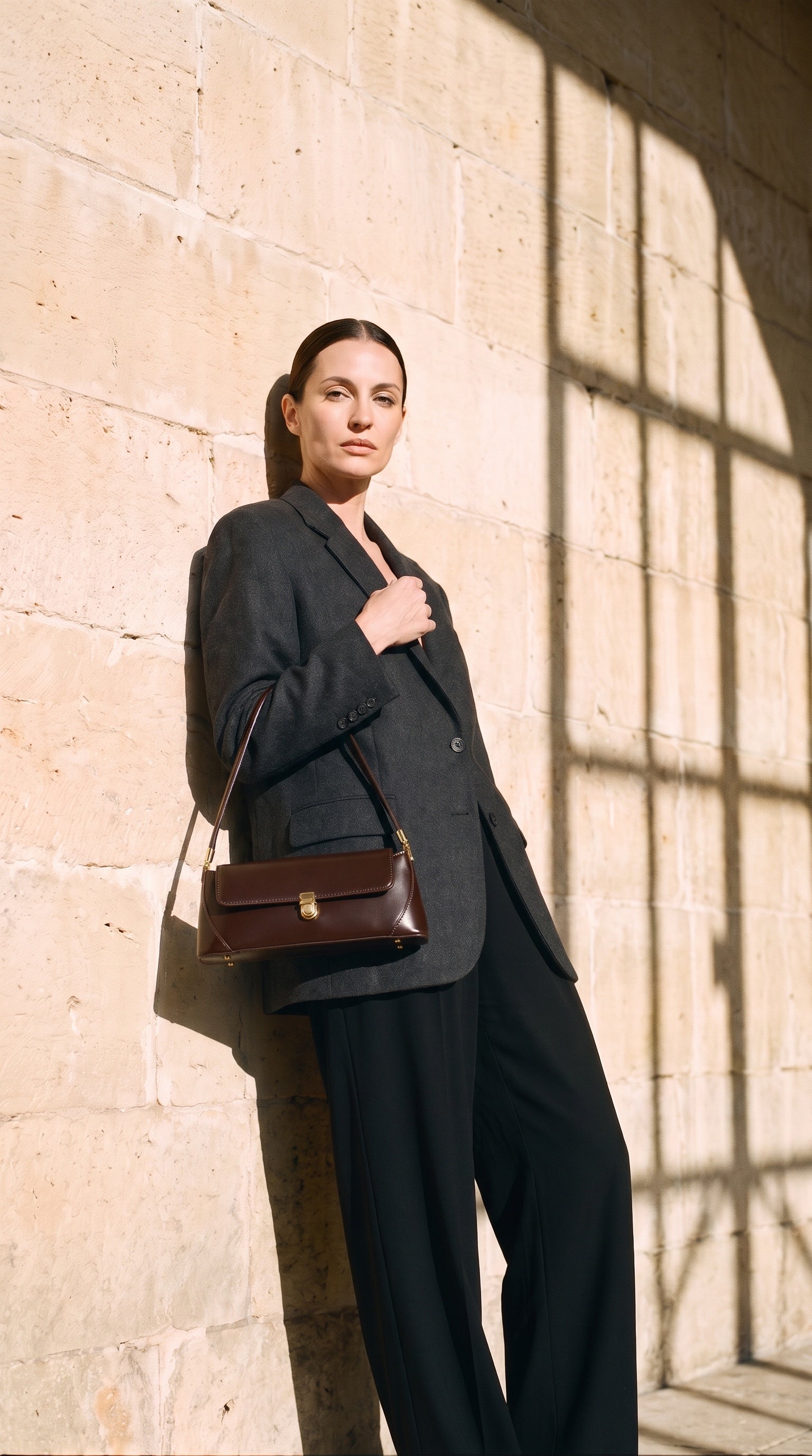 Sac AGATHE porté par le mannequin devant un mur de pierre