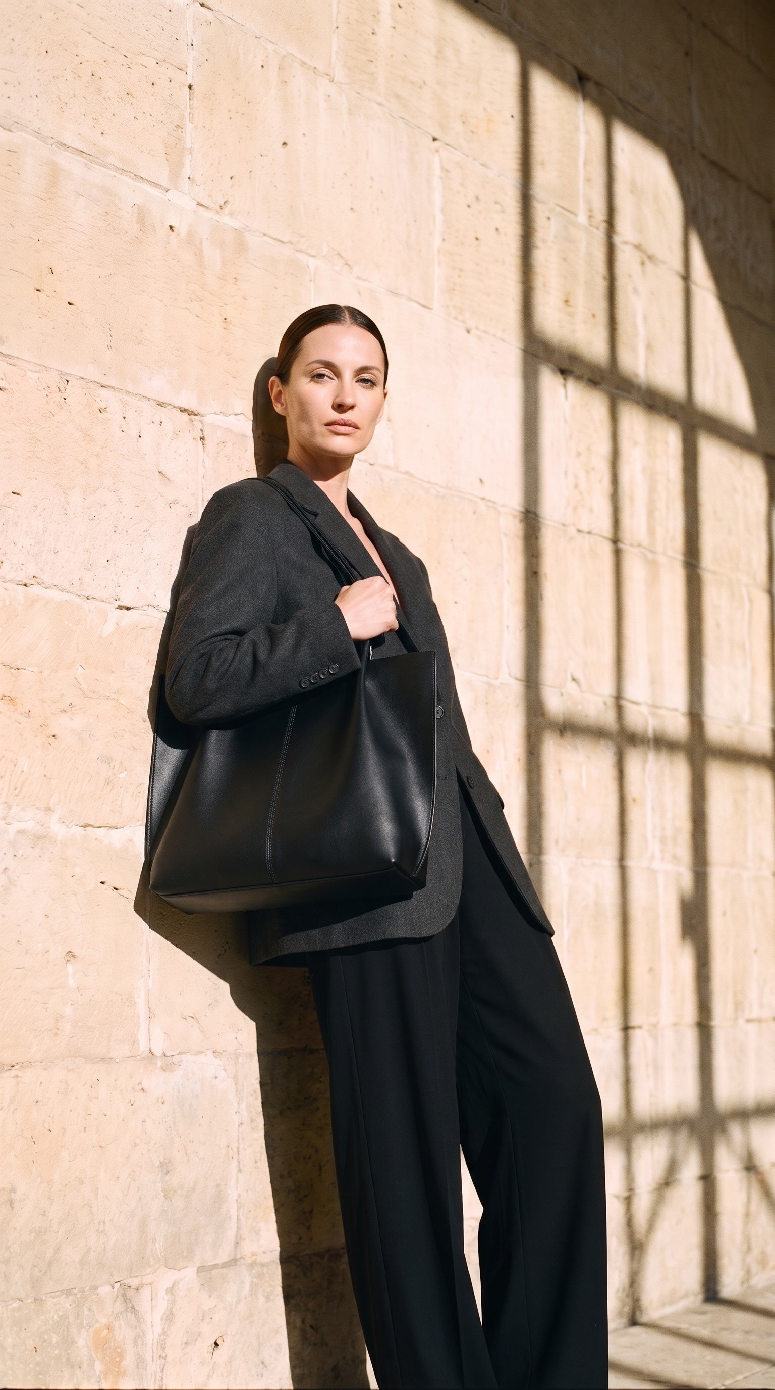 Sac ARIA porté par le mannequin devant un mur de pierre