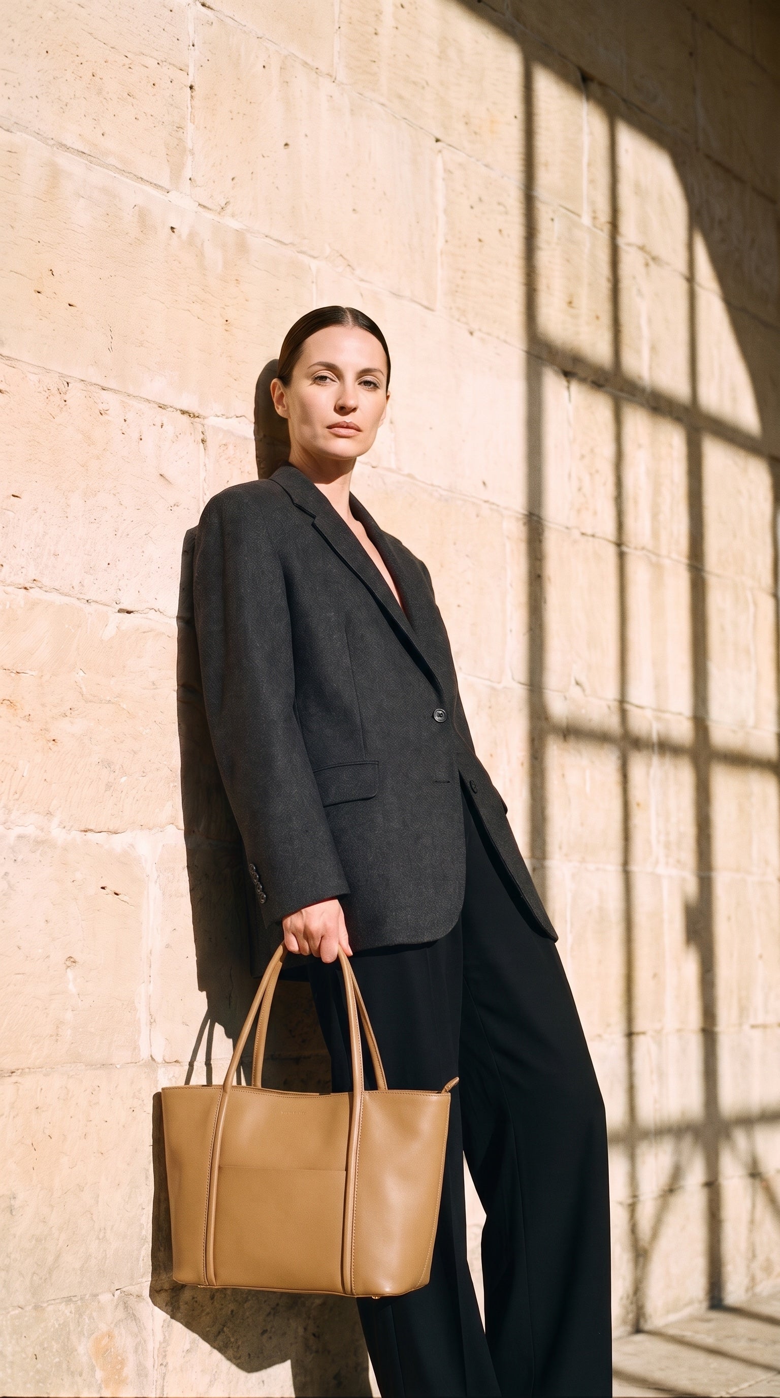 Sac CAMEO-L porté par le mannequin devant un mur de pierre