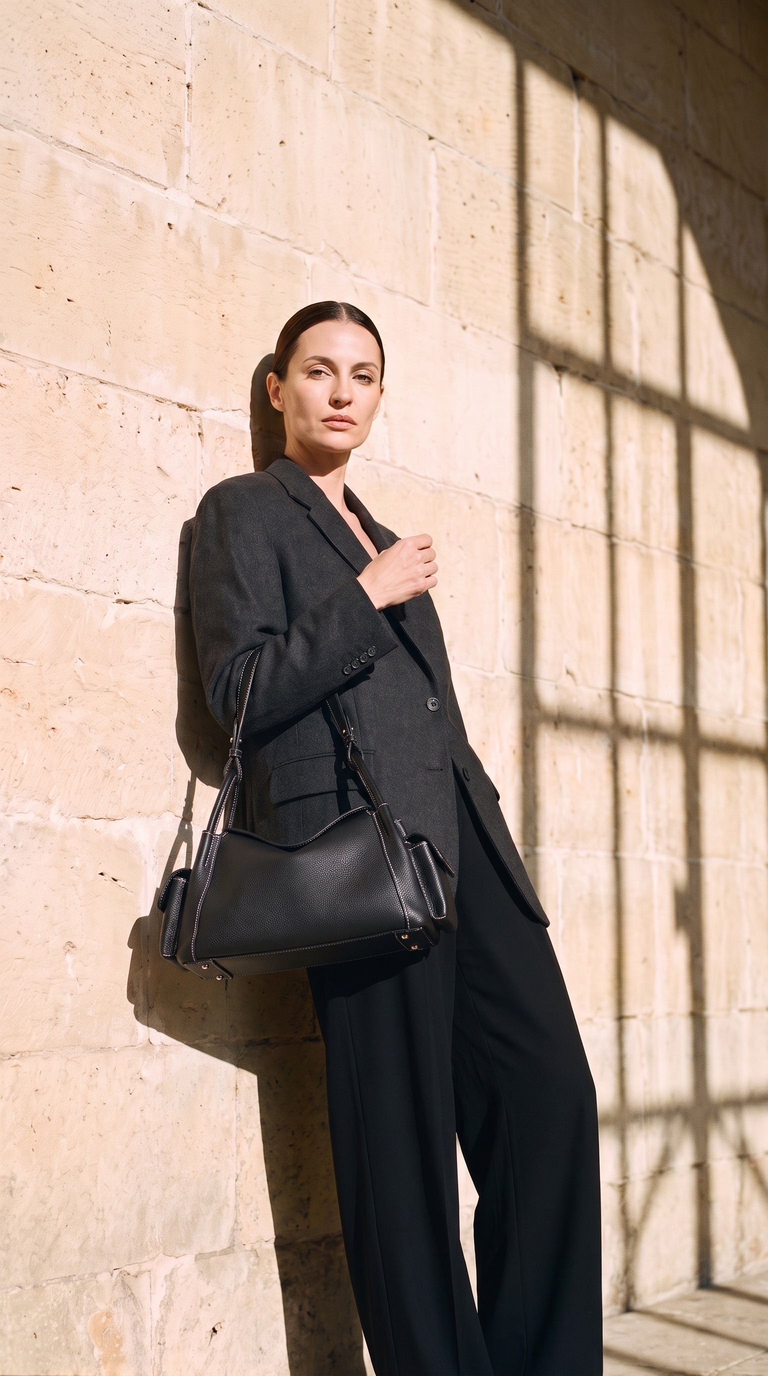 Sac CAMILLE porté par le mannequin devant un mur de pierre