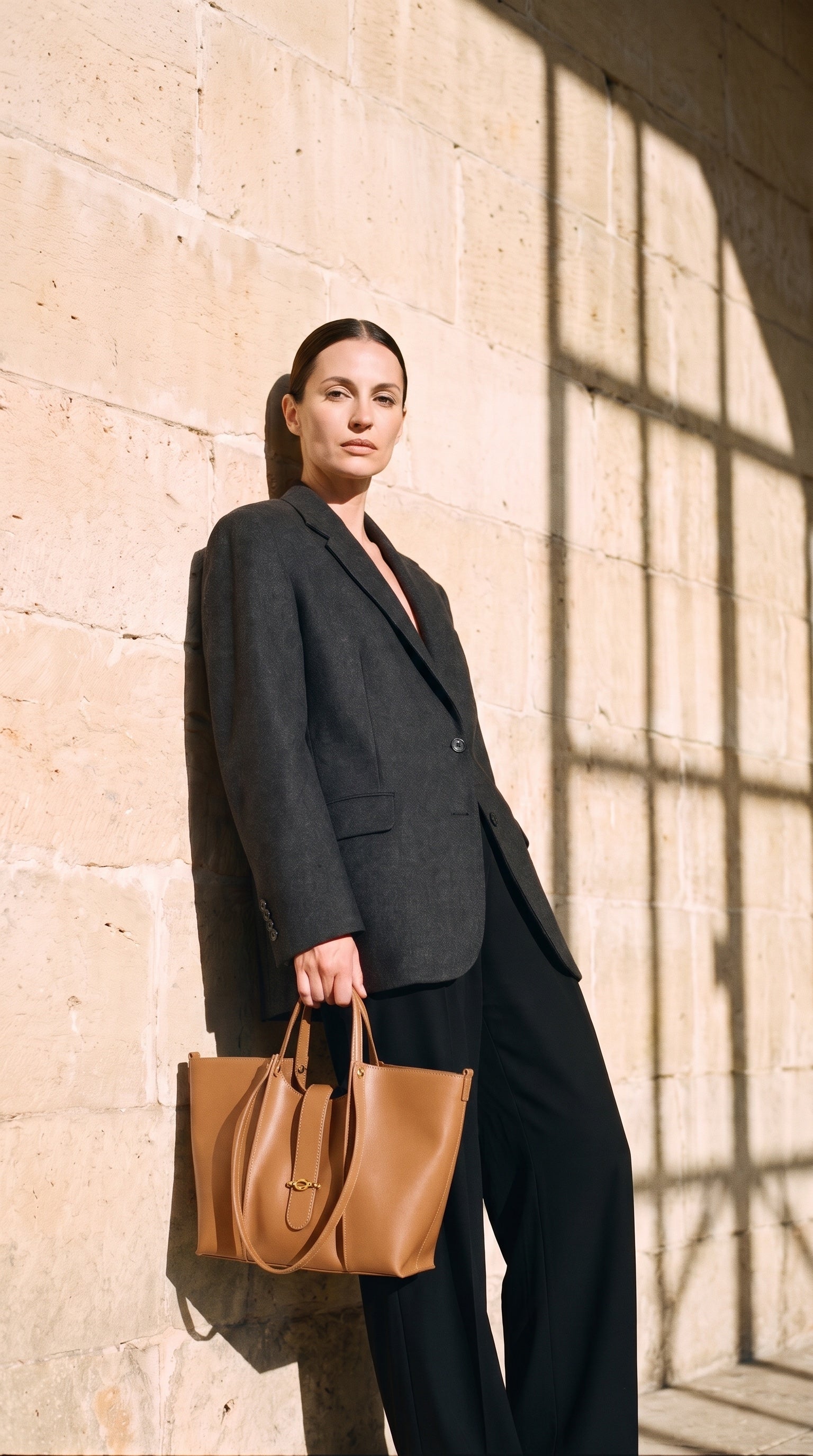 Sac GRACE porté par le mannequin devant un mur de pierre