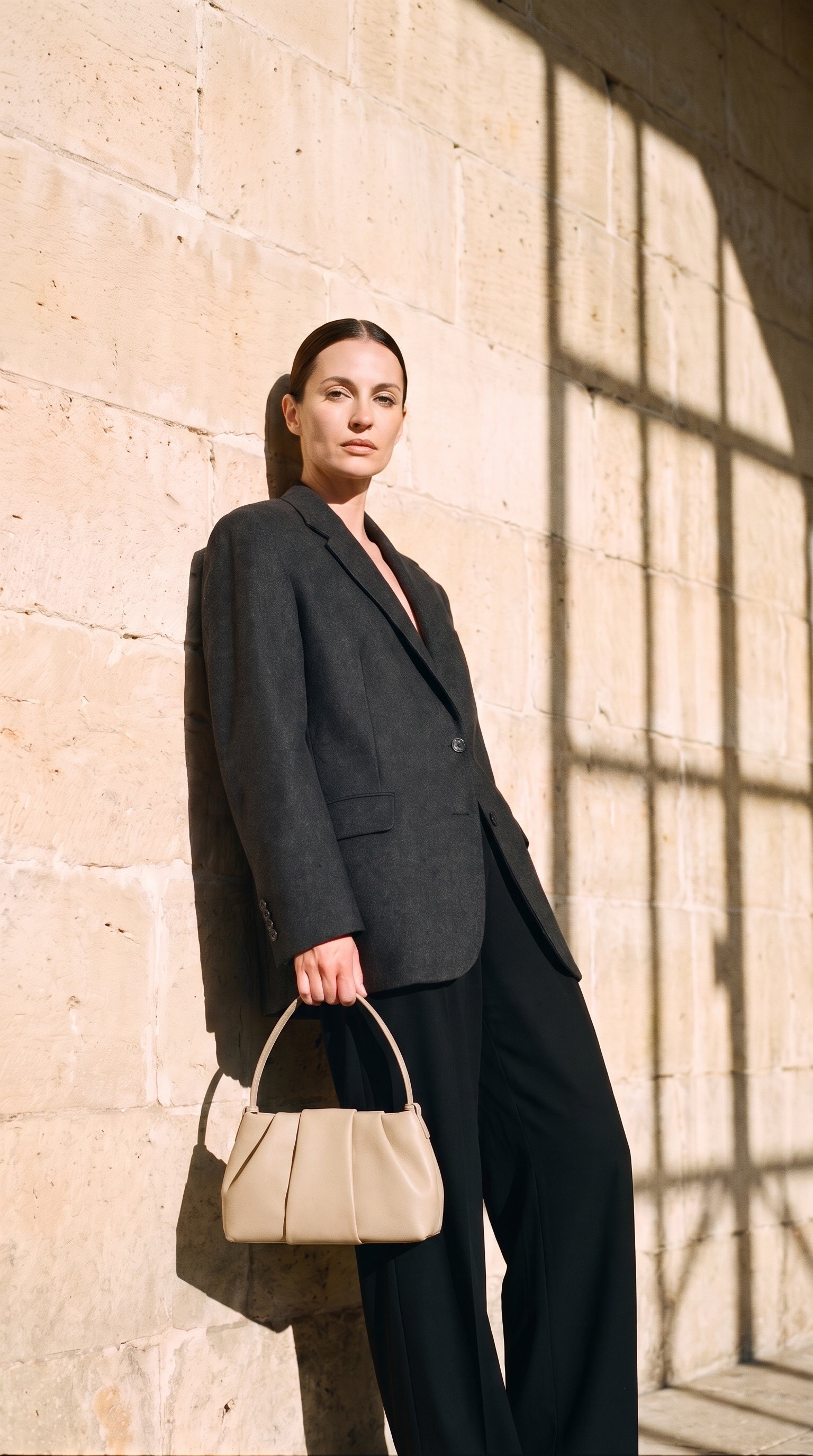 Sac JADE porté par le mannequin devant un mur de pierre