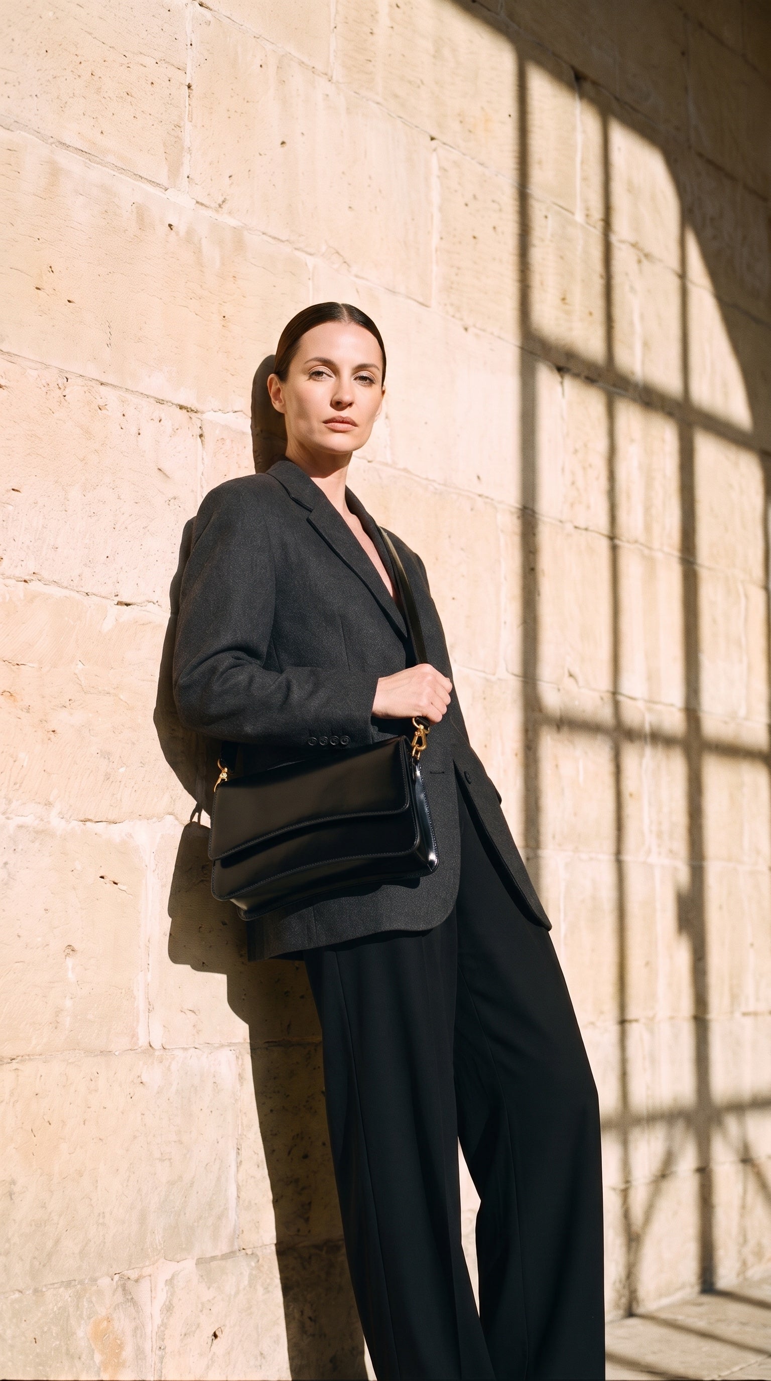 Sac LADYS porté par le mannequin devant un mur de pierre