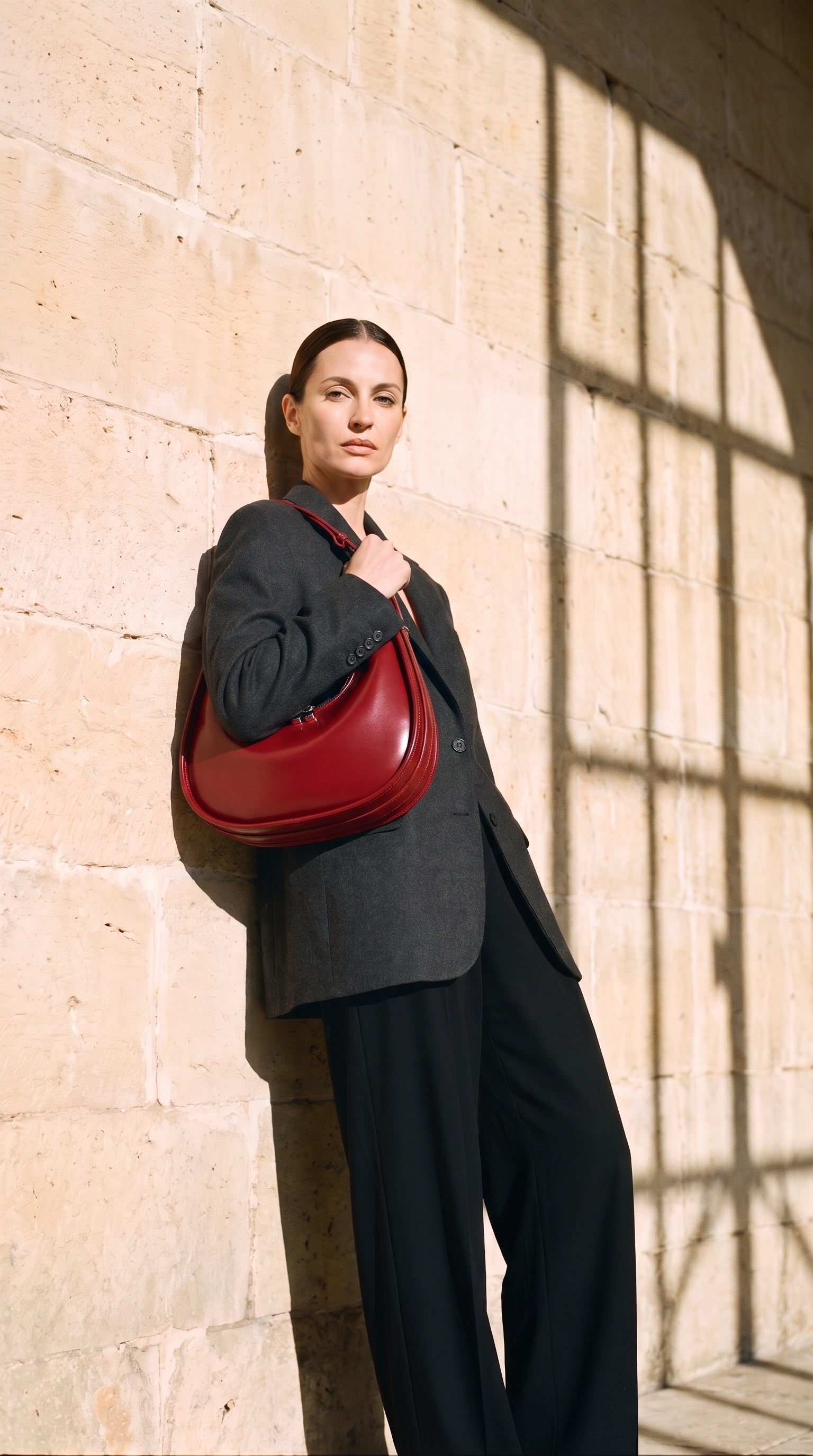Sac LEONIE porté par le mannequin devant un mur de pierre