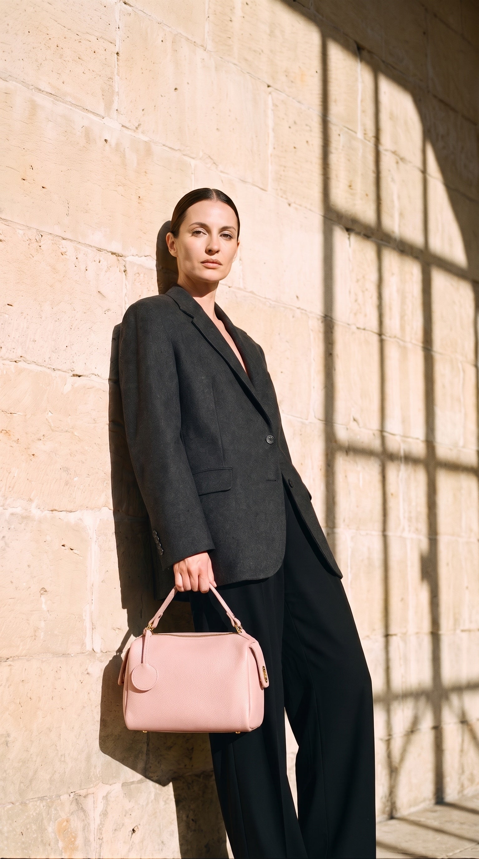 Sac LISA porté par le mannequin devant un mur de pierre