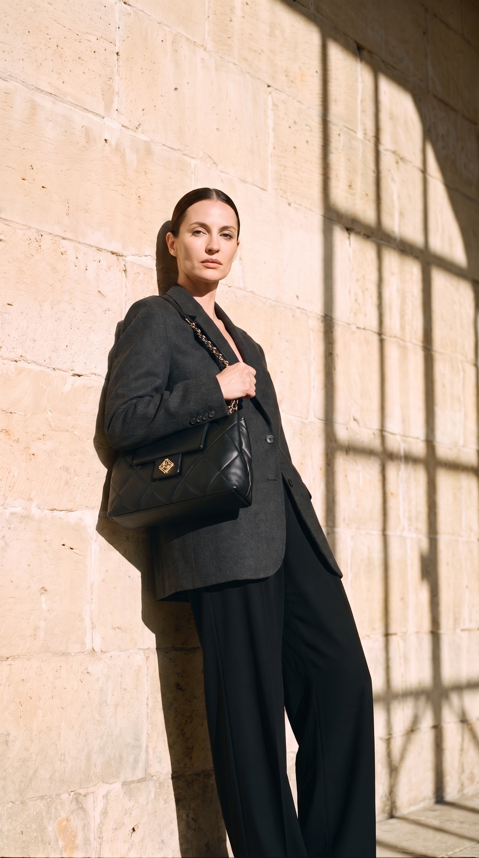 Sac LIVIA porté par le mannequin devant un mur de pierre