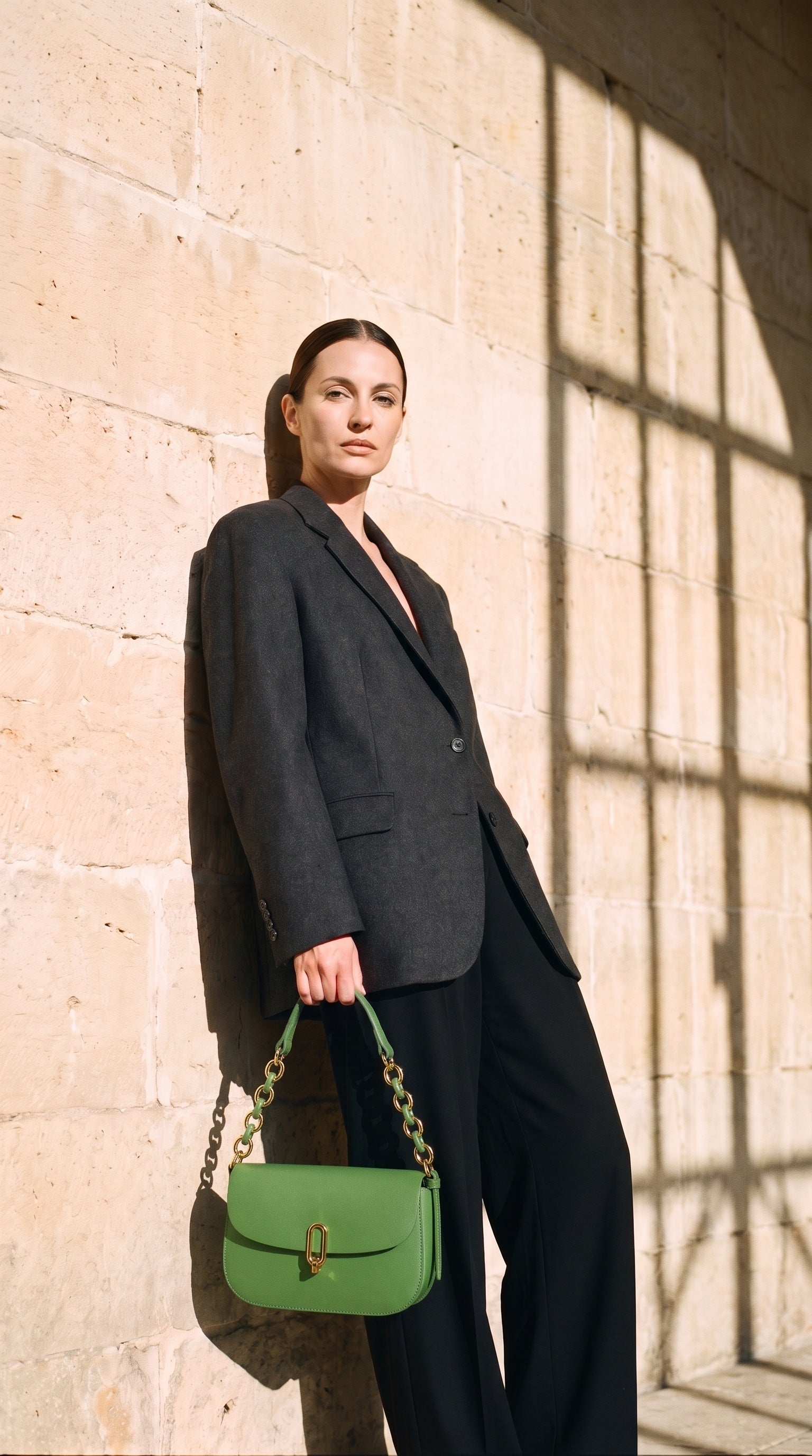 Sac NOEMIE porté par le mannequin devant un mur de pierre
