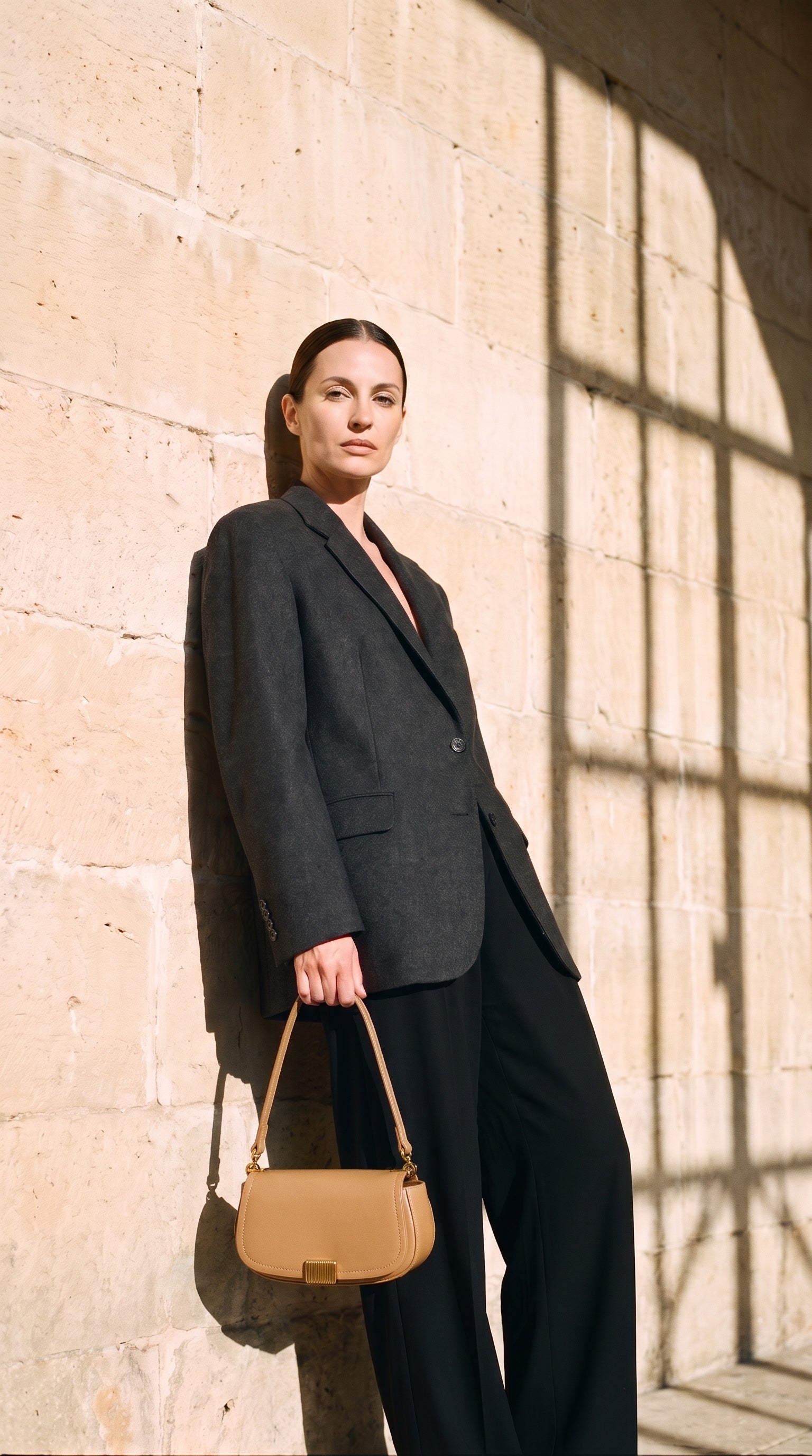 Sac YARA porté par le mannequin devant un mur de pierre